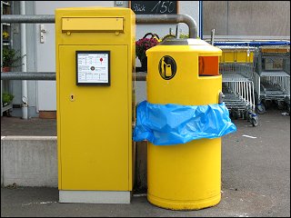 Briefkasten und Mülleimer vor einem Supermarkt
